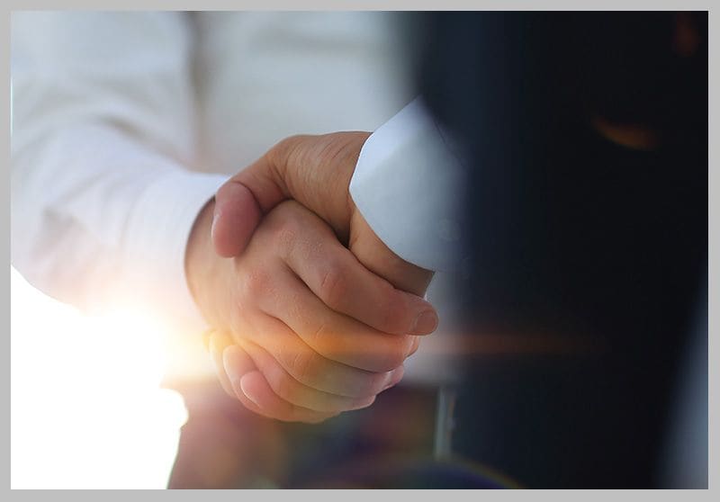 Two business people shaking hands across a desk